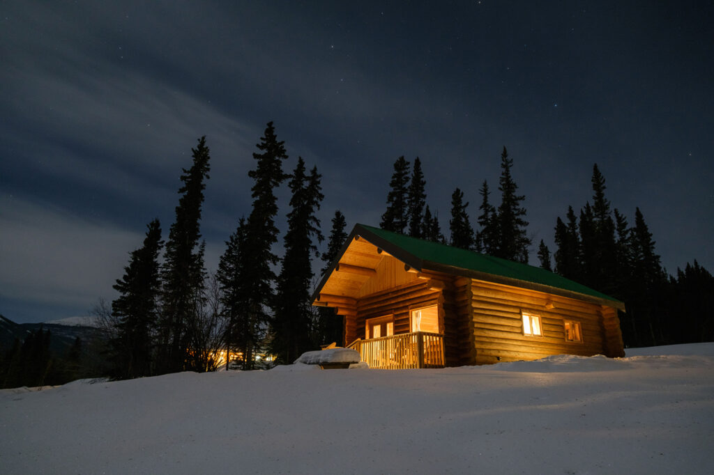 Cabin in the woods, Southern Lakes Resort in the Yukon. A log cabin with a snowy foreground.